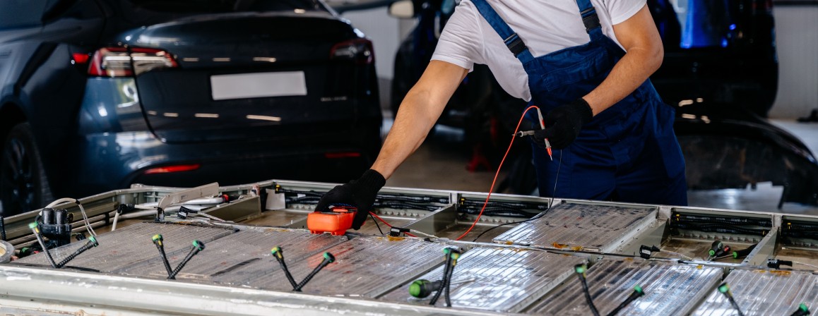 Technician testing an electric vehicle battery pack in a workshop.